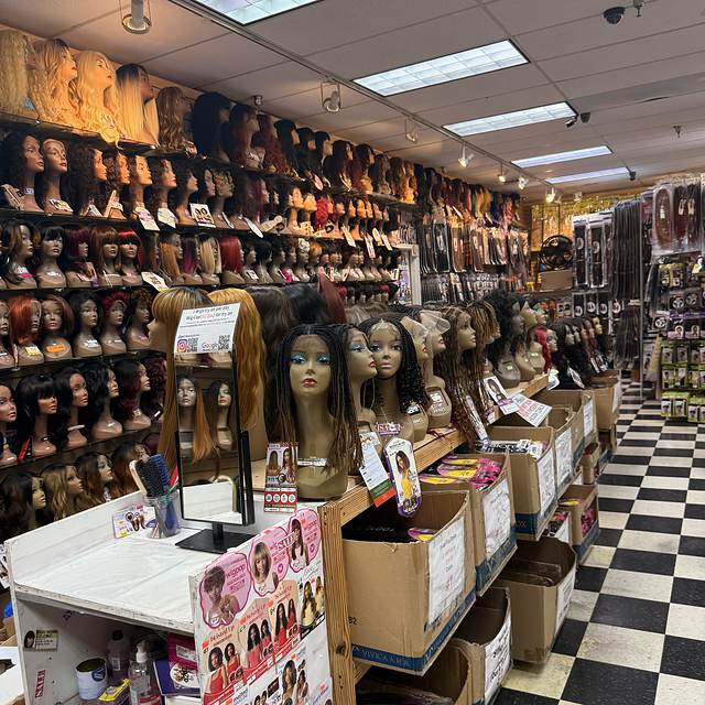 Wig section at Beauty Time, wall of styled wigs above the aisle