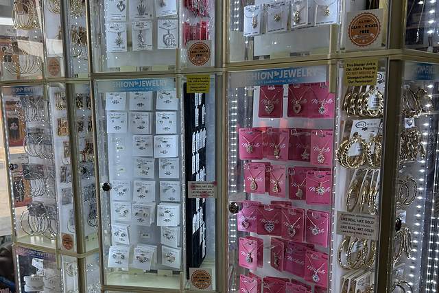 Lit jewelry cases at Beauty Time with gold hoop earrings, chains and pendant sets